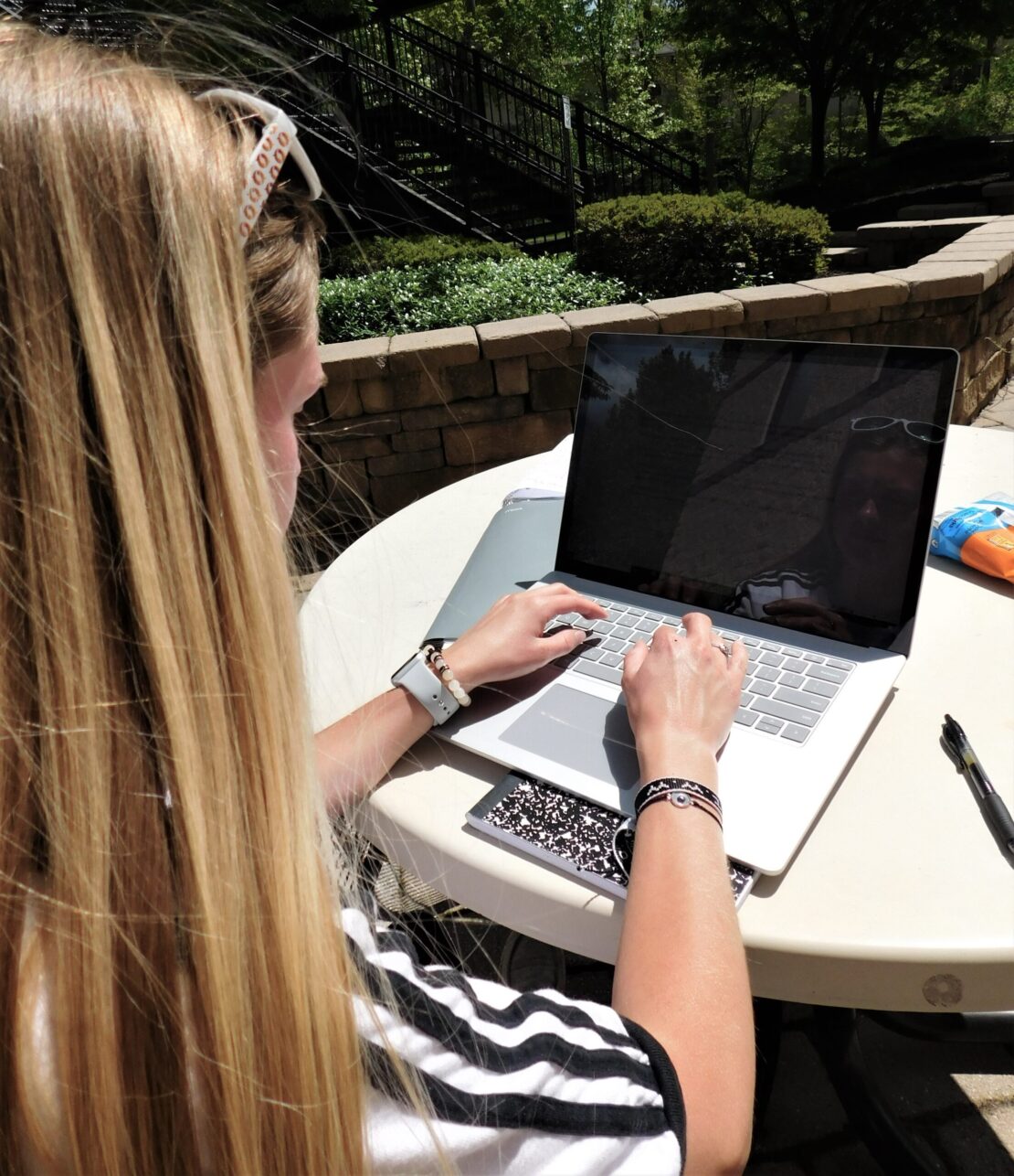 Blond woman working on laptop outside