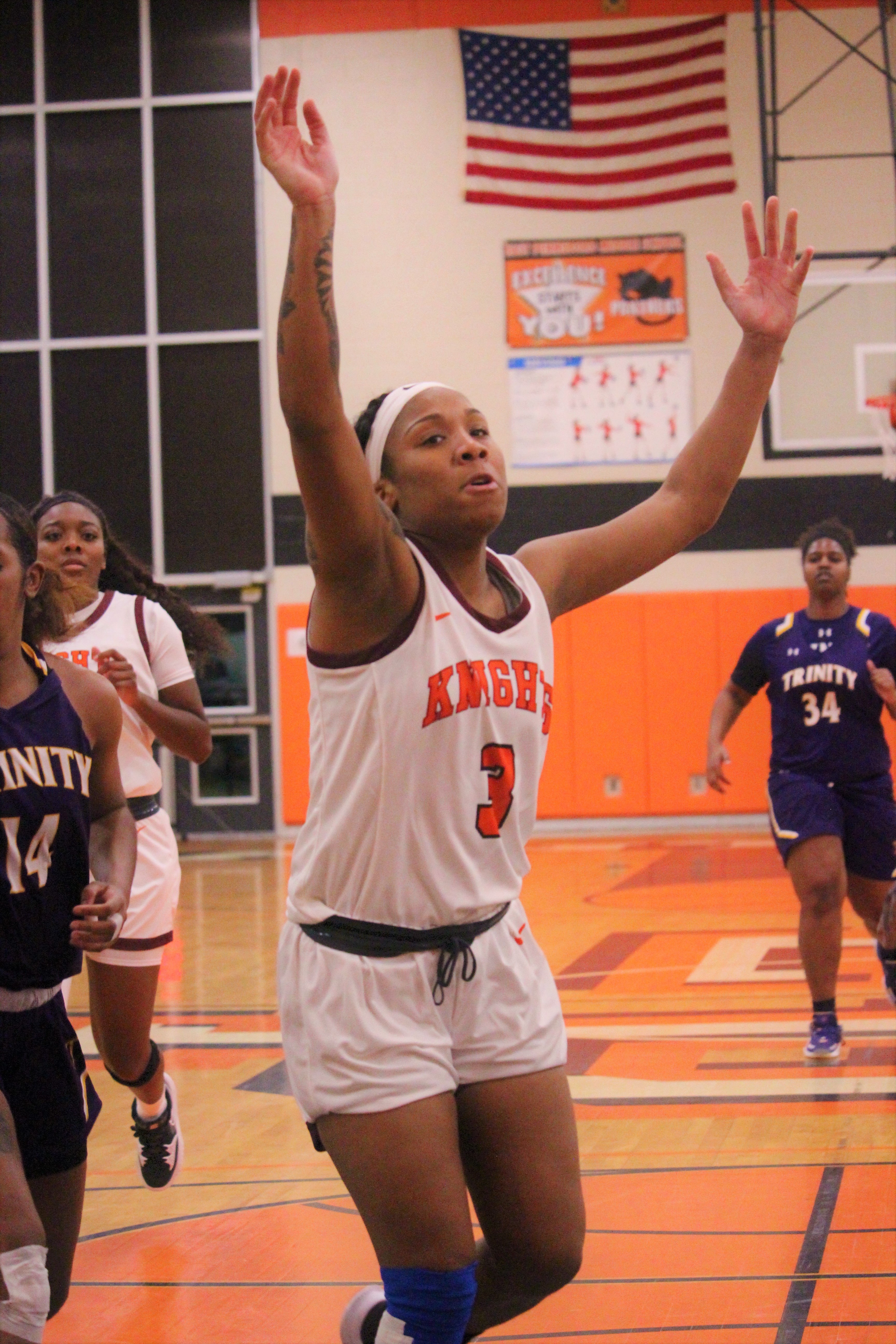 Woman -- Tahniyaah Jackson, No. 3, in an orange-on-white Knights jersey  -- Central Penn basketball player on the court signaling to a teammate to pass the ball in a 2023 game Trinity.