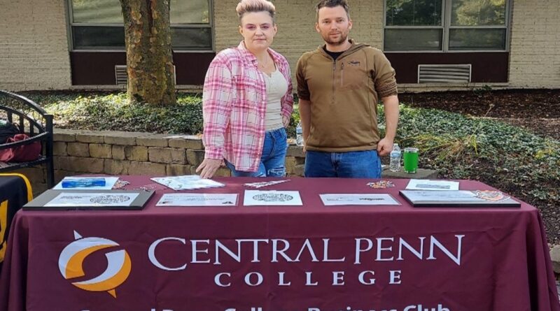 woman and man at a table with Central Penn College Business Club on a banner table cloth