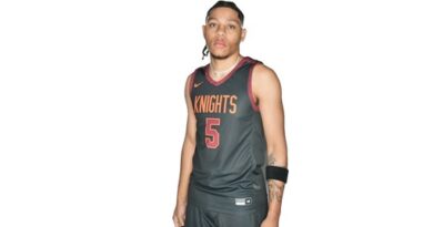 Young man black basketball uniform with Knights and number 5 on jersey front in orange, outlined in white