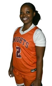 Young woman with hair bunched behind her head and wearing an orange-on-white basketball uniform with Knights and the number 2 on the front of the jersey