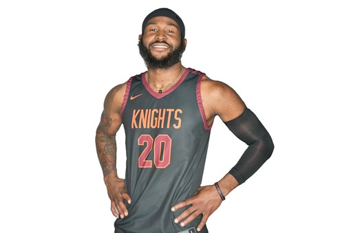 Young man with beard in an orange-on-gray tank top basketball uniform with Knights and the number 20 on the front of the jersey in orange and with white outline