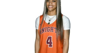 Young woman in an orange-on-white basketball uniform with Knights and 4 on the jersey front