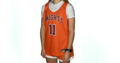 Smiling young woman with long blond hair in an orange-on-white basketball uniform with Knights and No. 11 on the front of the jersey