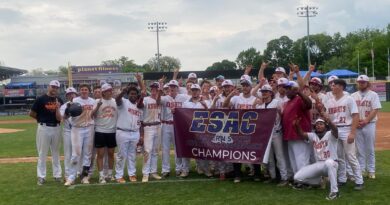 Wide shot of a college baseball team, holding a maroon banner that says Easter States Athletic Conference Champions