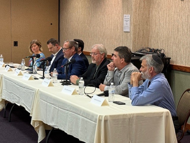 Seated in a row next to one another at two 10-foot tables that are draped in shite tablecloths, in the Central Penn College Conference Center, are, from right, Ron Muroff, rabbi of Chisuk Emuna Congregation, Harrisburg; Mike Martine, senior pastor of Trinity Luthern, Mount Joy; Brad Hoge, Chad Hogue, senior pastor at New Hope Church (Brethren in Christ), Harrisburg; Eric Failing, executive director of the Pennsylvania Catholic Conference; partially hidden is Dillon Epler, St. John’s Evangelical Lutheran Church, Tamaqua; Dauphin County Commissioner Justin Douglas; and Samantha Bise, professor of humanities and social sciences at Penn State Hazelton and Lehigh Valley, and at Lehigh Carbon Community College. Photo by Diane McNaughton