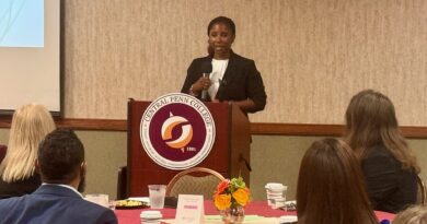 Wpoman in business attire at Central Penn College podium addressing a ballroom of people in the college's conference center during the 2025 Business Partner of the Year. Kim Craig