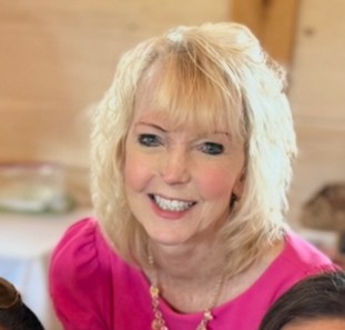 Smiling woman with blond hair. Portrait photo of writer Diane McNaughton.