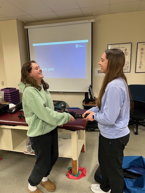 Carli Failla and Rylee King test the robotic arm's strength.