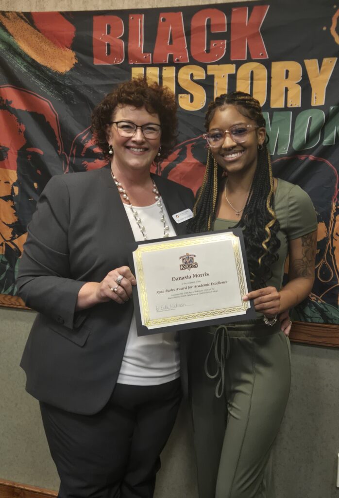Central Penn College Associate Vice President of Student Services Erika Wilkinson and Central Penn student Danasia Morris standing together, smiling, and each holding a side of Danasia's certificate for The Rosa Parks Award for Academic Excellence.