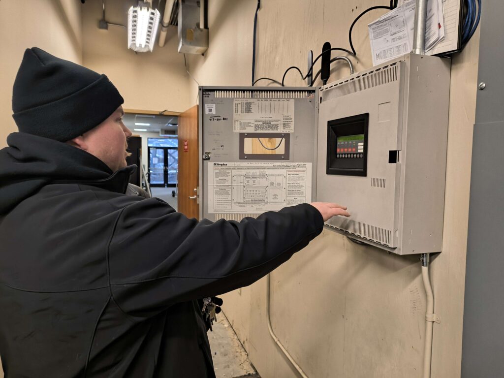 Mrakovic checks the fire-alarm controls in the Advanced Technology Education Center (ATEC).