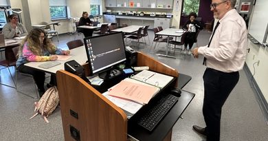 Professor Christopher Adams talking to some students before a medical-assisting class.
