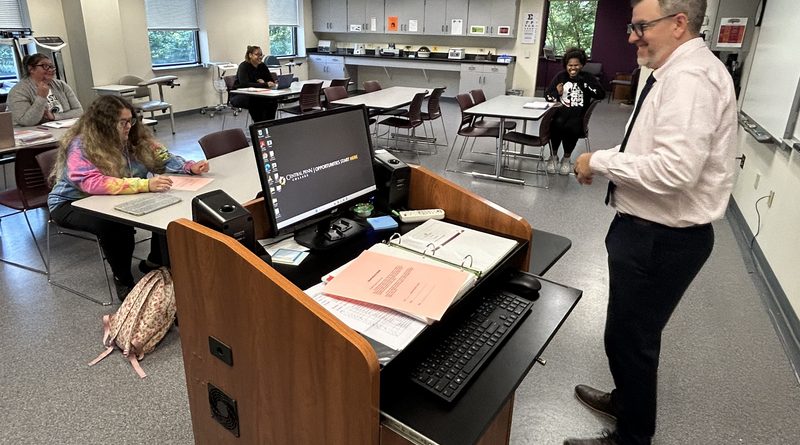 Professor Christopher Adams talking to some students before a medical-assisting class.